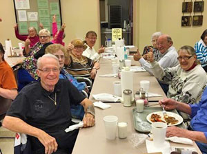 Seniors enjoying a community meal at a long table